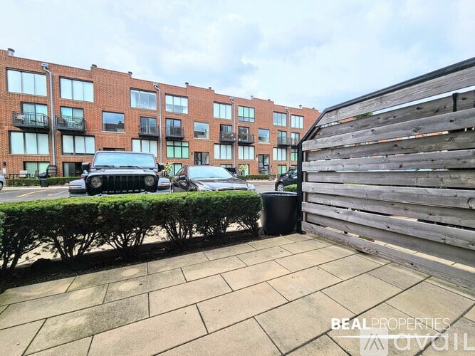 A BEAL PROPERTIES sign is on a wooden fence in front of a brick building.