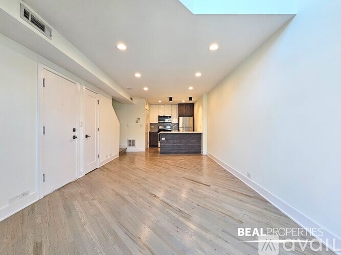 A spacious room with wooden flooring and white walls.