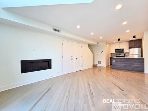 A spacious living room with a fireplace and hardwood floors.