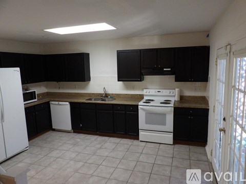 A kitchen with black cabinets and white appliances.