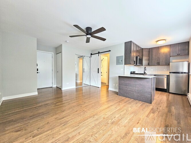 A spacious kitchen with wooden floors and a ceiling fan.