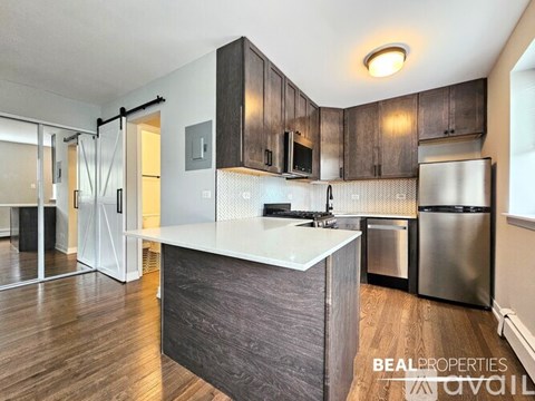 A modern kitchen with dark wood cabinets and stainless steel appliances.