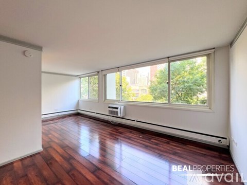 A spacious room with wooden flooring and a large window.