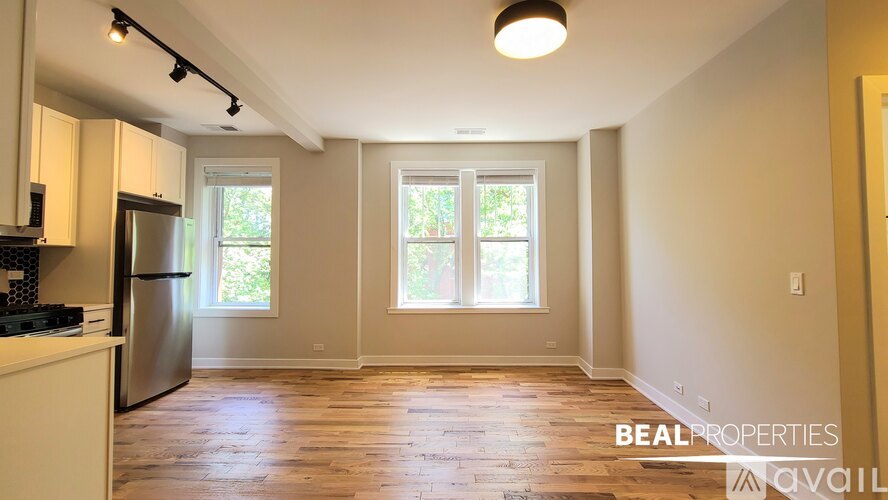A room with wooden floors and a window with blinds.