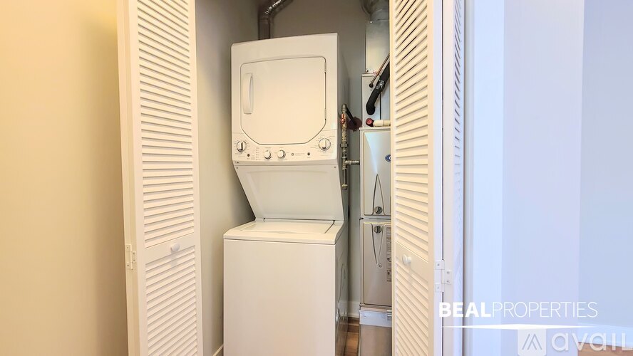 A white dryer is sitting next to a white door in a room.