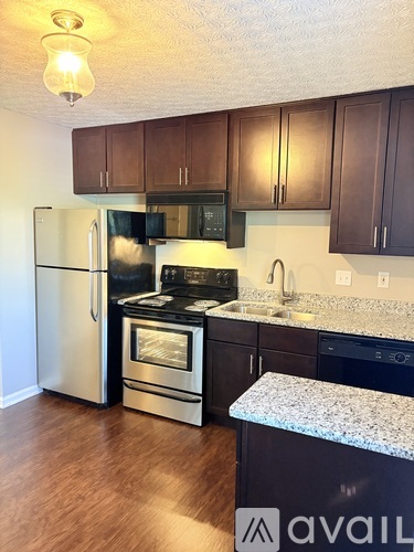A kitchen with a refrigerator, microwave, oven, and sink.