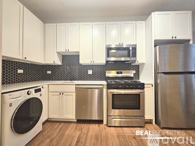 A kitchen with white cabinets and a stainless steel refrigerator.