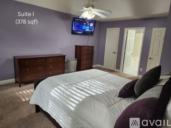A bedroom with a bed, dresser, and television in Suite I, which is 378 square feet.