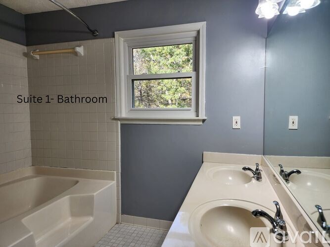 A bathroom with a tub, sink, and window.