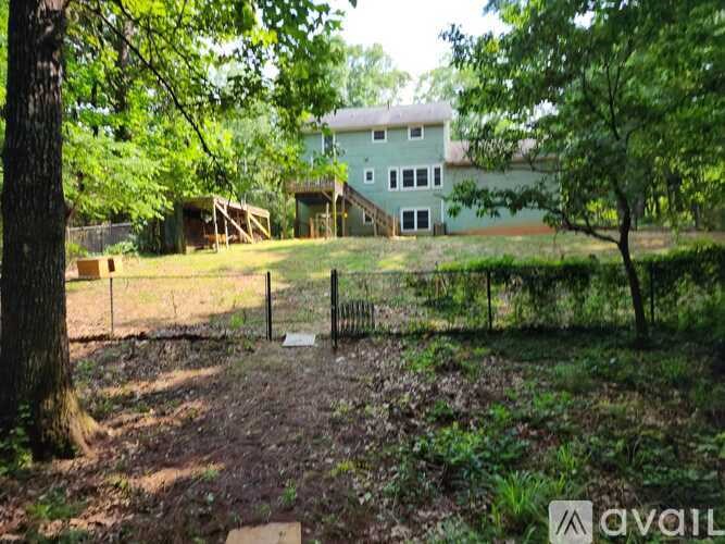 A house is surrounded by trees and a fence in the yard.