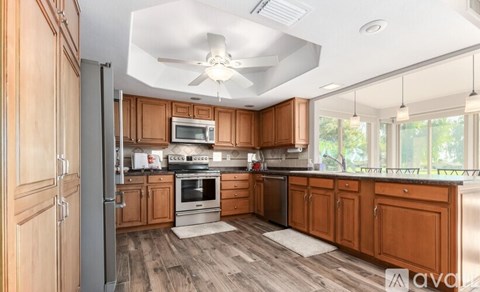 A kitchen with wooden cabinets and a white ceiling fan.