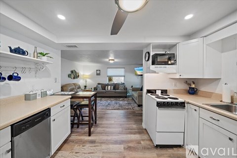 A kitchen with white cabinets and a wooden floor.
