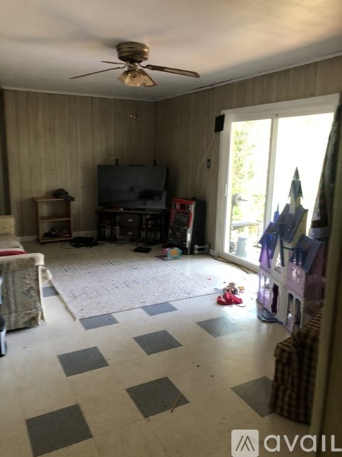 A living room with a television and a ceiling fan.