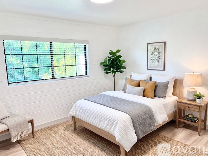 A bedroom with a large bed and a window with blinds.