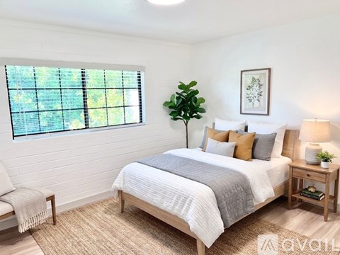 A bedroom with a large bed and a window with blinds.