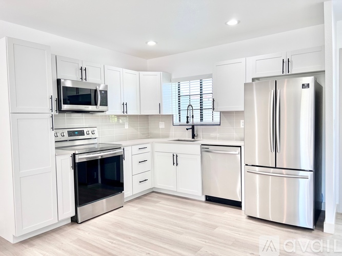 A modern kitchen with white cabinets and stainless steel appliances.