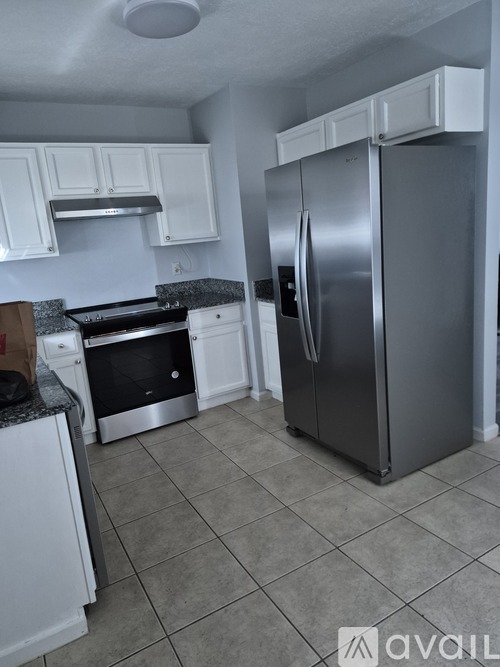 A kitchen with a stainless steel refrigerator and white cabinets.
