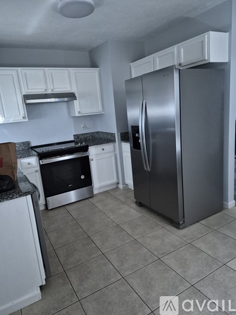 A kitchen with a stainless steel refrigerator and white cabinets.