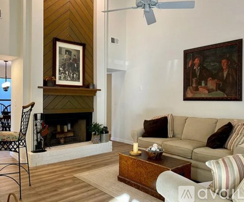 A living room with a fireplace, a couch, a chair, and a painting on the wall.