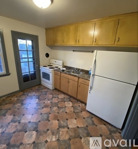 A kitchen with a white fridge, wooden cabinets and a tiled floor.