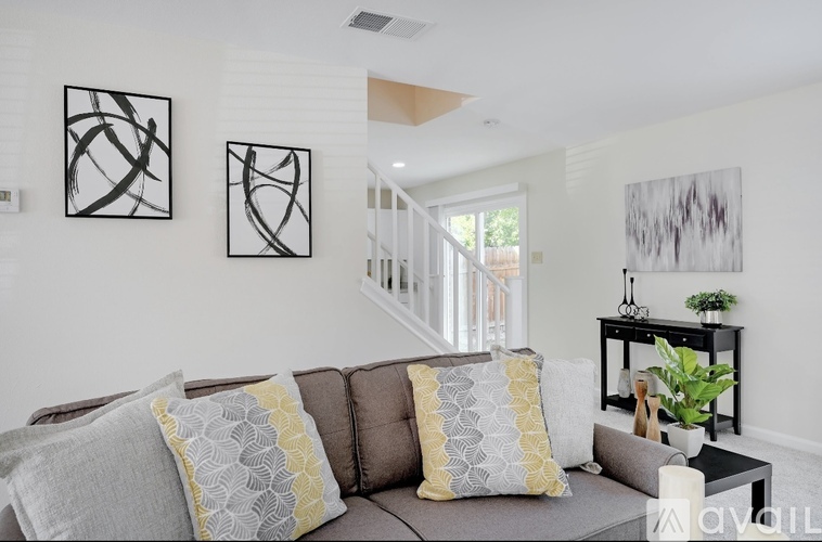 A living room with a grey couch and a painting on the wall.