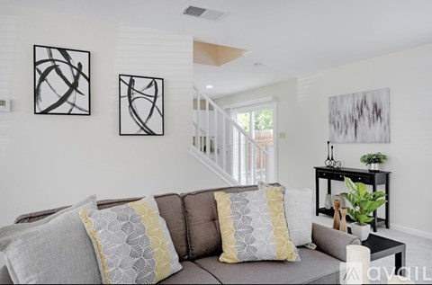 A living room with a grey couch and a painting on the wall.