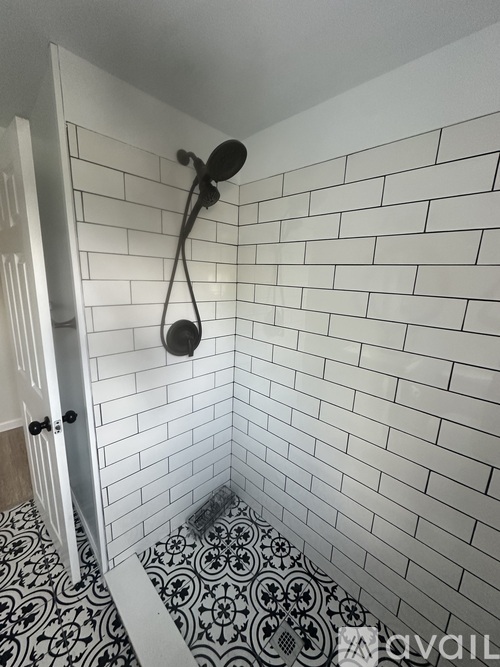 A white tiled bathroom with a black and white floor.