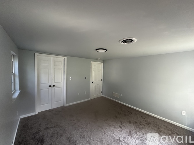 A room with grey carpet and white walls.