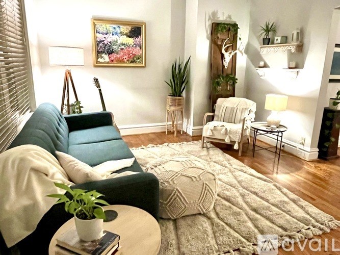 A living room with a blue couch, a white chair, and a rug.