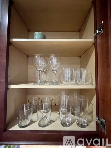 A cabinet with glasses on the shelf.