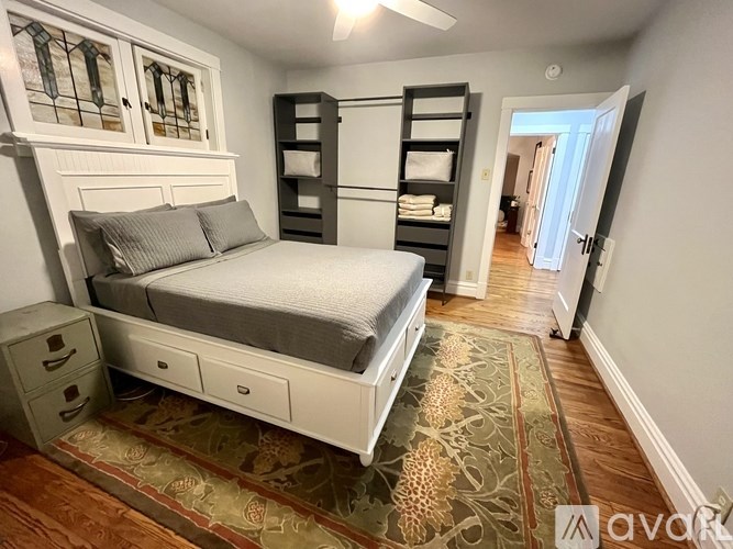 A bedroom with a bed, drawers, and a rug.