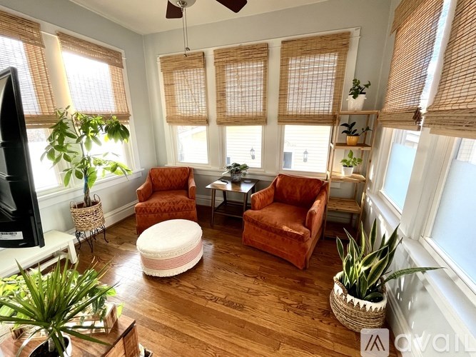A living room with wooden floors and a television on the left side.