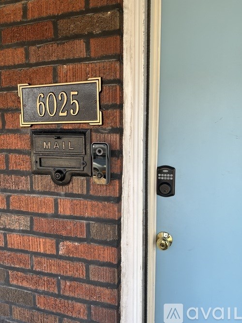 A blue door with a mail slot and a sign above it that says 6025.