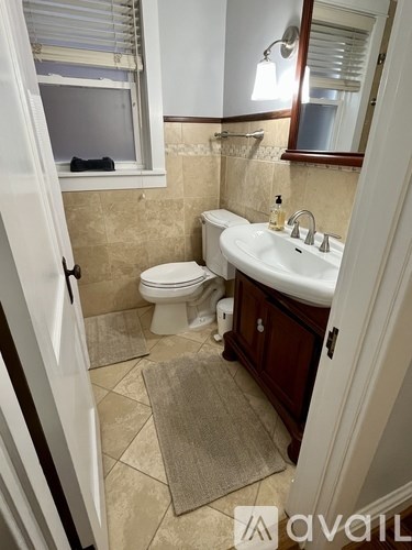 A bathroom with a toilet, sink, and mirror.