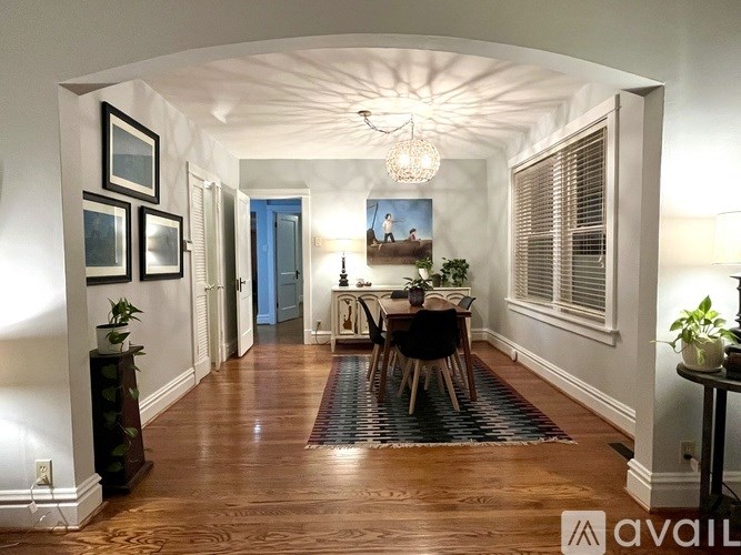 A black metal bench with blue cushions is on a brick porch.