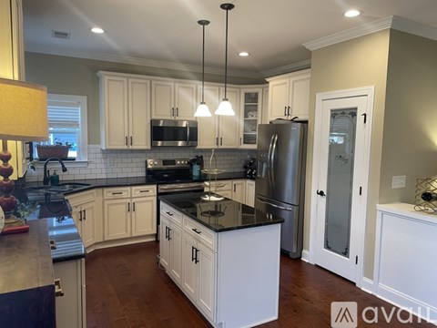 A kitchen with white cabinets and a black countertop.