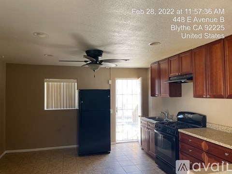 A kitchen with a black fridge, black stove, and a ceiling fan.