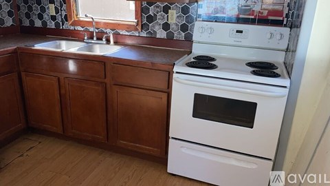 A kitchen with a white stove and wooden cabinets.