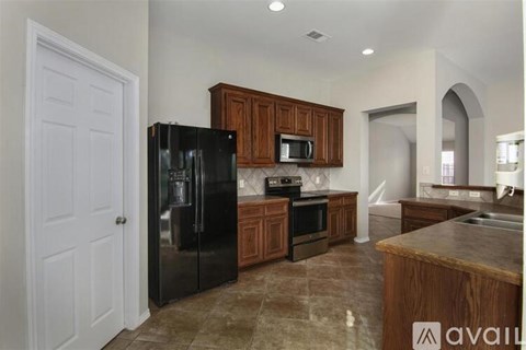 A kitchen with a black fridge, microwave, oven and sink.