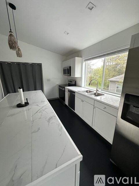 A kitchen with white cabinets and a marble countertop.