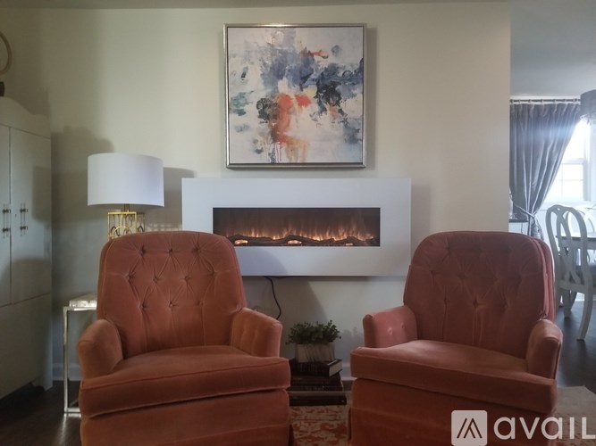 Two red chairs are in front of a fireplace in a room.