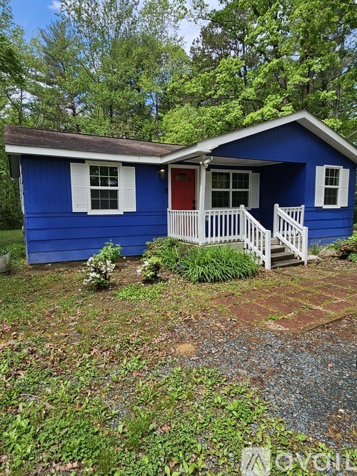 A small blue house with a red door and white railings.
