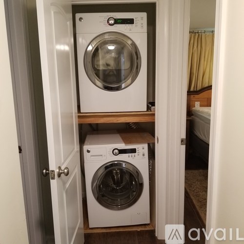 Two washing machines are stacked on top of each other in a small space.