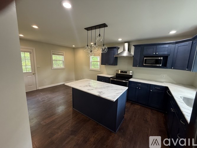 A kitchen with dark blue cabinets and a wooden floor.