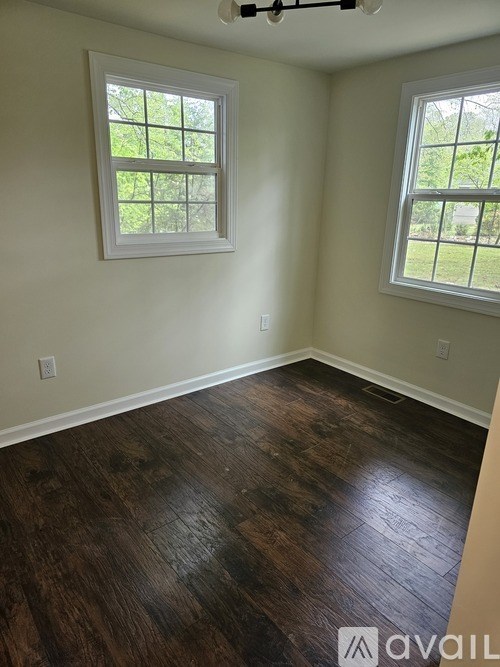 A room with wooden floors and two windows.