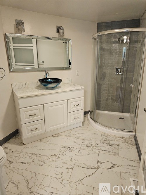 A bathroom with a marble floor and a glass shower stall.