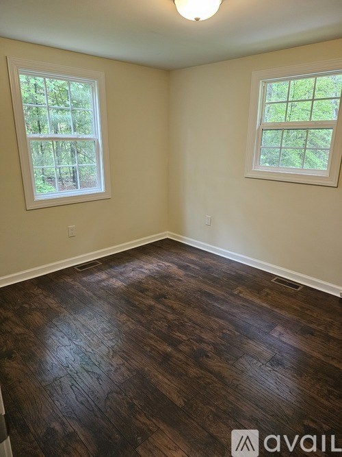 A room with wooden floors and two windows.
