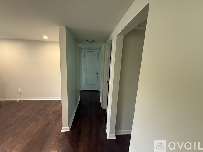 A hallway with a door at the end and a wooden floor.