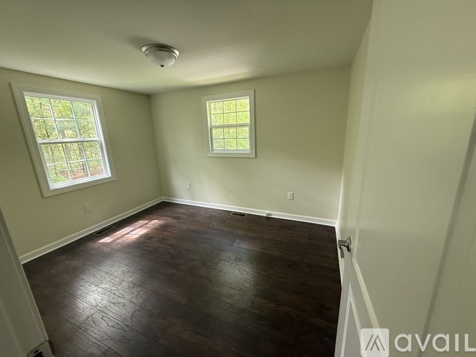 A room with a wooden floor and two windows.