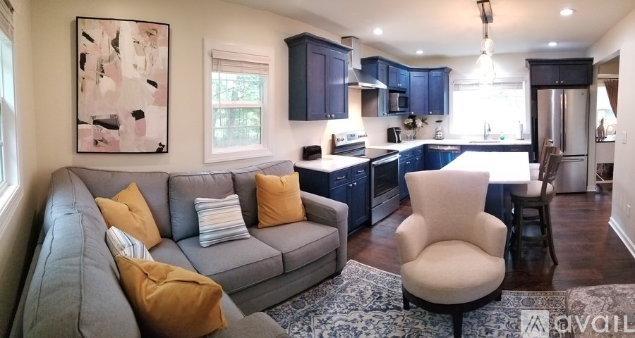 A living room with a grey couch and a painting on the wall.